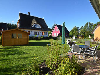 Gartenansicht mit Terrasse und Gartenhaus, in dem z.B. Fahrräer untergestellt werden können