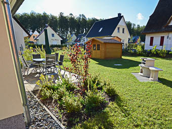 Ferienhaus Godewind Glowe - Blick in den Garten mit Terrasse, Grill und Gartenhaus, in dem Fahrräder untergestellt werden können